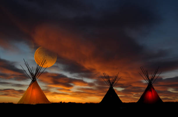 Teepee camp at sunset with full moon stock photo