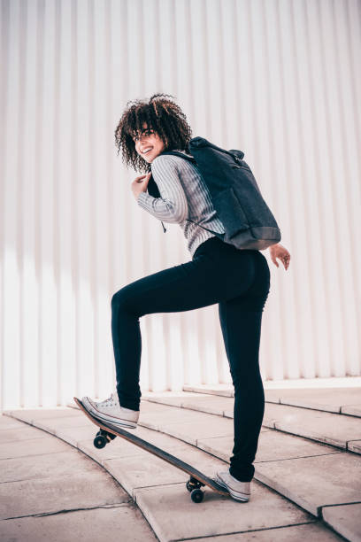 istock Cute Female With Curly Hair Posing With Backpack and Skateboard 956207802