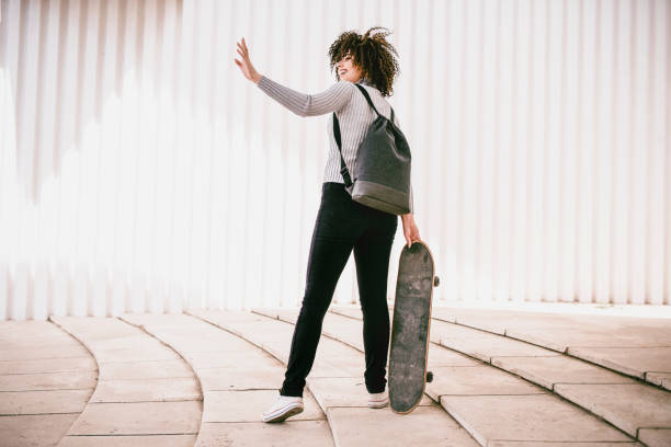 istock Cute Female With Curly Hair Posing With Backpack and Skateboard 956207872