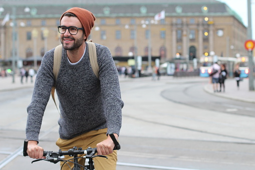 Stylish man riding a bicycle in the city with copy space.