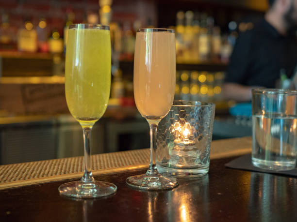 istock Two wineglasses filled with mimosa drinks sitting on a bar counter top 956214660