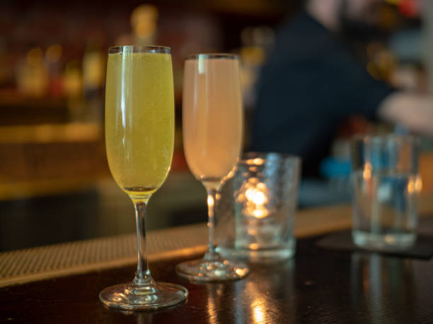 istock Two wineglasses filled with mimosa drinks with bartender in background 956215534