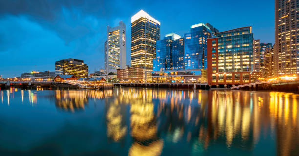 Skyline and Fort Point Channel in downtown Boston Massachusetts USA Panoramic stock photograph of Fort Point Channel, the skyline of Boston, Harborwalk promenade and Boston Tea Party, Massachusetts, USA at twilight blue hour. harborwalk stock pictures, royalty-free photos & images