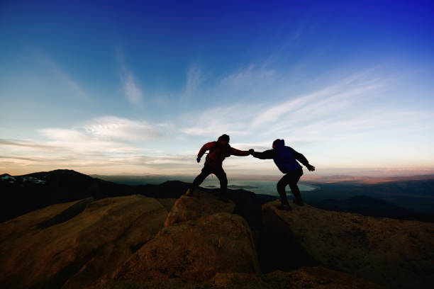 istock Friends help each other on top of a mountain 956218276