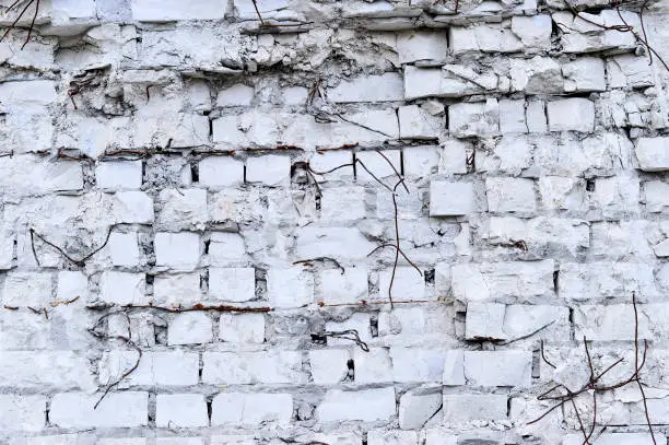 Photo of Part of the wall of white brick with pieces of rebar of an old building for demolition. Black and white image