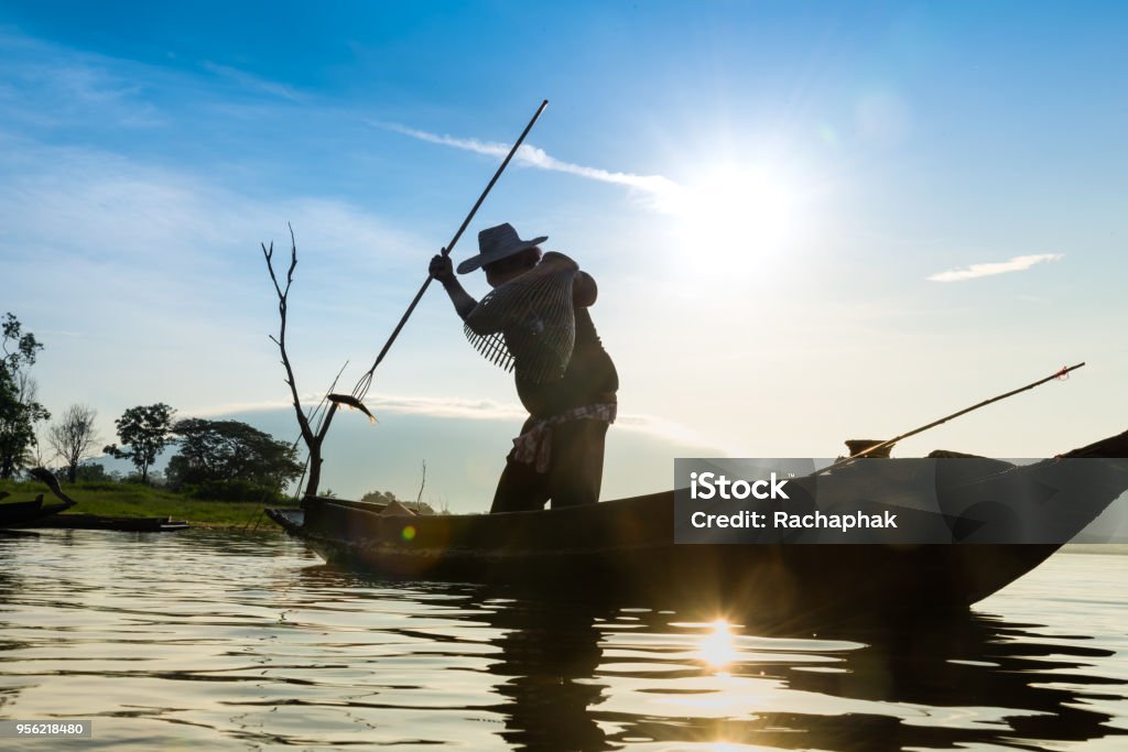 Silhouette of fishermen using coop-like trap catching fish in lake with beautiful scenery of nature morning sunrise. Beautiful scenery at Bang-Pra, Chonburi Province Thailand. Adult Stock Photo