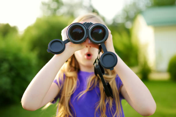 istock Funny little girl looking through binoculars on sunny summer day 956221776