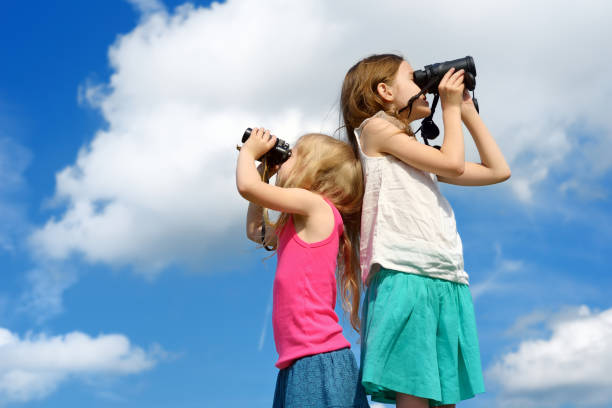 istock Two cute little girls looking through binoculars on sunny summer day 956221878