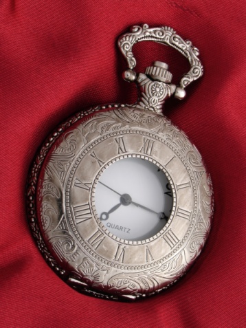 Old beautiful pocket watch lying in the beach sand.