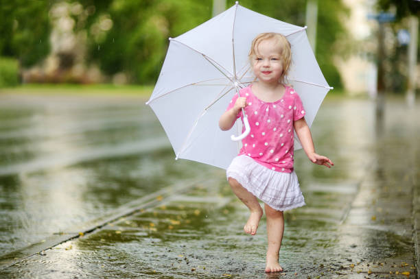 lindo niño niña divirtiéndose bajo una lluvia - child dancing preschooler outdoors fotografías e imágenes de stock