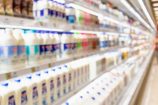 Abstract blur supermarket grocery store refrigerator shelves with fresh milk bottles and dairy products