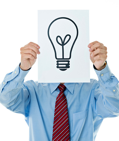 Businessman holding a paper with light bulb symbol against white background.