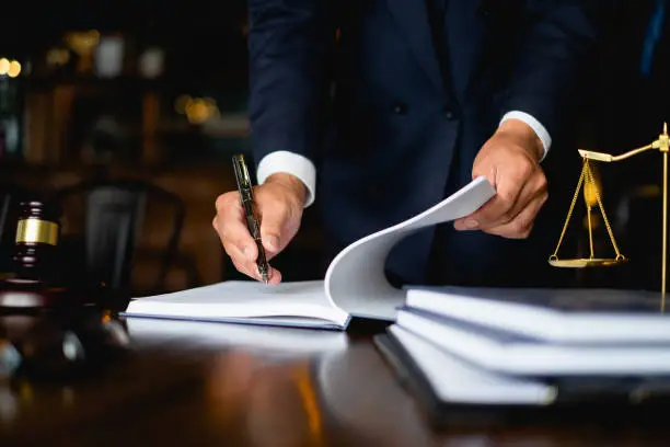 Photo of Close up lawyer businessman working or reading lawbook in office workplace for consultant lawyer concept.