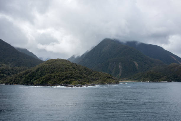 Stunning lush mountain landscape with coastal rock under a misty morning sky in Milford Sound in the Fiordland National Park in New Zealand.