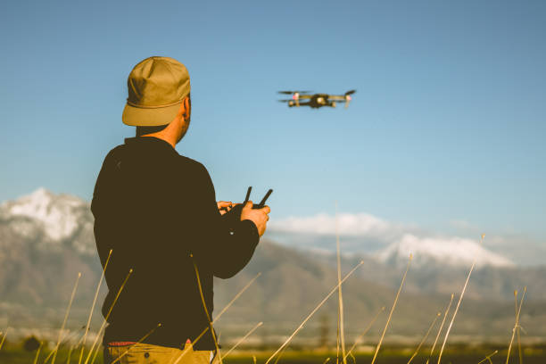 młody człowiek latający dronem o zmierzchu z górami w tle - skill agriculture horizontal outdoors zdjęcia i obrazy z banku zdjęć