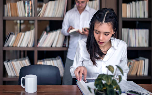istock College female student sitting at desk and reading at library 956250176