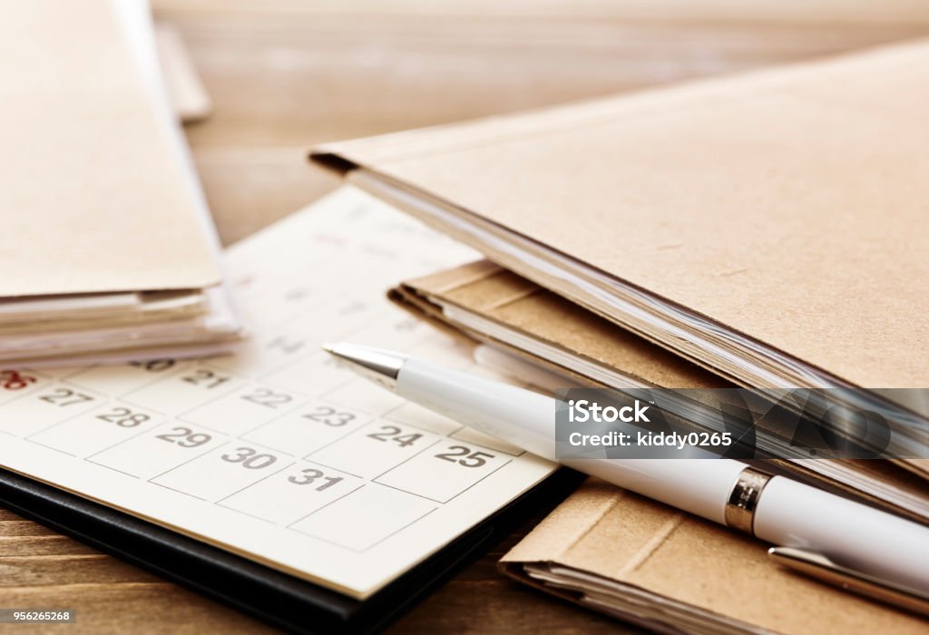 Calendar. Pile of papers paperwork and dead line. Calendar on office wooden desk table. With copy space. Calendar Stock Photo