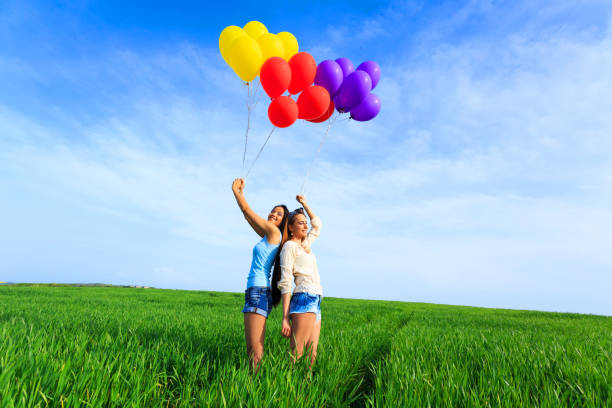 istock Cheerful young women holding multicolored balloons 956265548