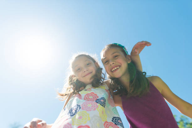 istock Two elementary-age ethnic girls posing together at the park on a sunny day 956272470