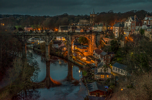 a classic view of Knaresborough viaduct at night showing the river and houses and a church