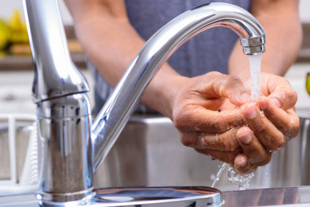 istock Man washing hands at kitchen sink for meal preparation 956273500
