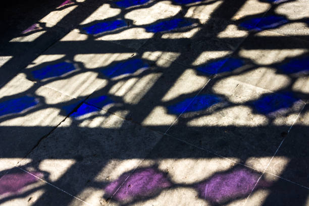 Colorful light projected on old tiles through strained-glass window
