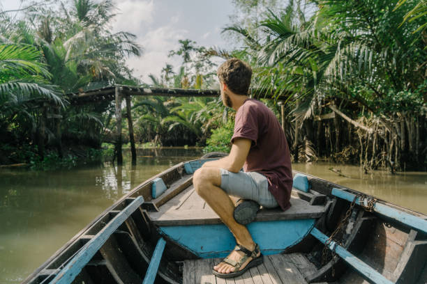 istock Man  riding on boat through Mekong delta and floating market 956276572