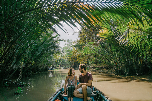 Young Caucasian woman riding on boat through Mekong delta in Vietnam