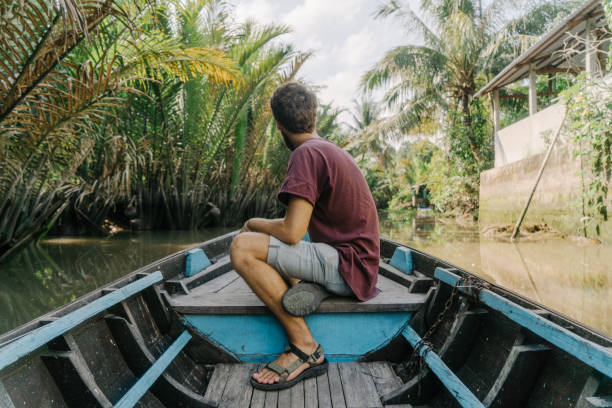 istock Man  riding on boat through Mekong delta and floating market 956276576