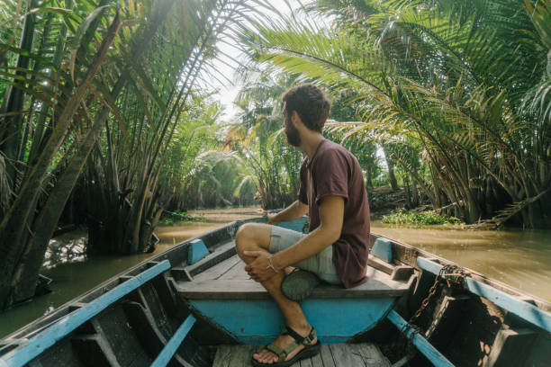 istock Man  riding on boat through Mekong delta and floating market 956276578