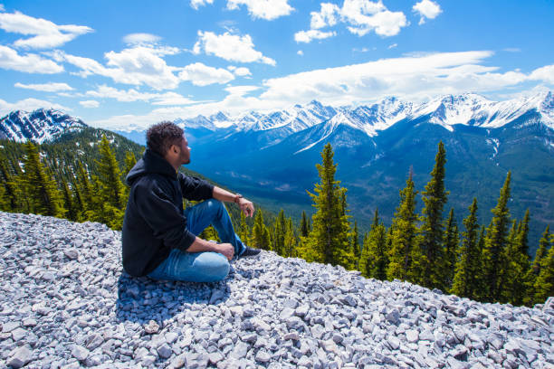 Man standing in front of stunning mountains and green landscape in Banff.