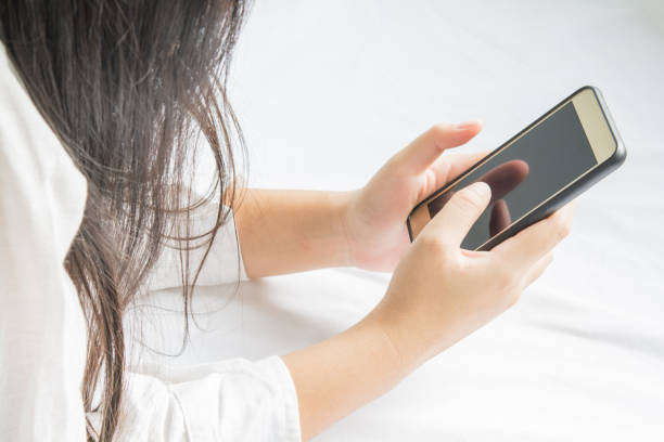 istock Phone in hands of women  on bed 956285052