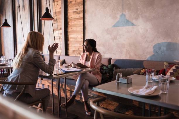 高級レストランでコーヒーを持っている 2 つのビジネス女性を破る - two people business lunch multi ethnic group meeting ストックフォトと画像