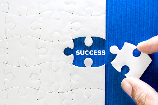 Close up piece of white jigsaw puzzle with SUCCESS text , concept of business challenge success completion with teamwork