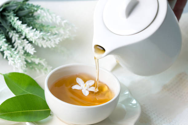 Close up pouring hot jasmine tea in a white tea cup ,  Tea ceremony time concept stock photo