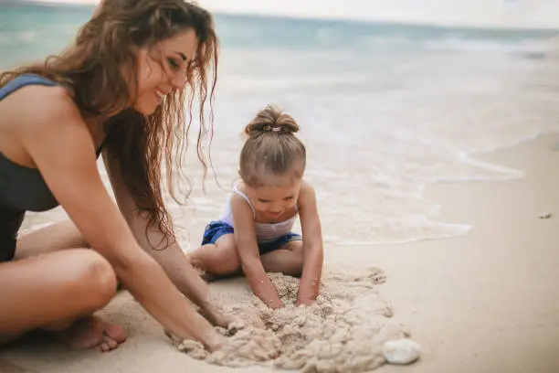 Photo of Children's Day. Mom and baby playing near beach