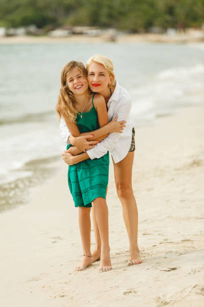 istock mother and little daughter embracing on beach looking at camera 956301186