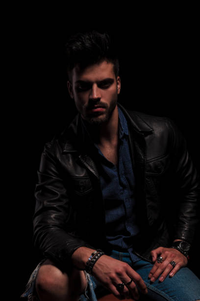 istock seated fashion man in leather jacket resting elbow on knee 956301840