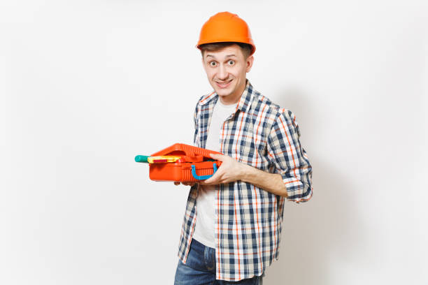 istock Young fun crazy handsome man in protective orange hardhat holding case with instruments or toolbox isolated on white background. Instruments, tools for renovation apartment room. Repair home concept. 956306458