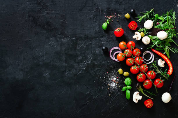 istock Fresh vegetables, herbs, onion, mushrooms, basil and spices on black background. Copy space 956307338