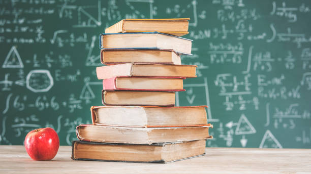 istock Books with apple in front of green chalk board 956308198