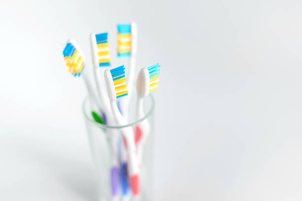 grupa plastikowych białych szczoteczek do zębów w różnych kolorach w szkle na białym tle. wolne miejsce na kopiowanie. - toothbrush dental hygiene dental equipment rainbow zdjęcia i obrazy z banku zdjęć