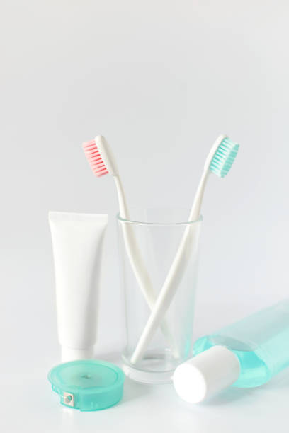 zahnbürsten, zahnpasta, spülen und handtuch auf weißem hintergrund. zahnmedizinische und medizinische konzept. kostenloses exemplar raum. - toothbrush pink turquoise blue stock-fotos und bilder