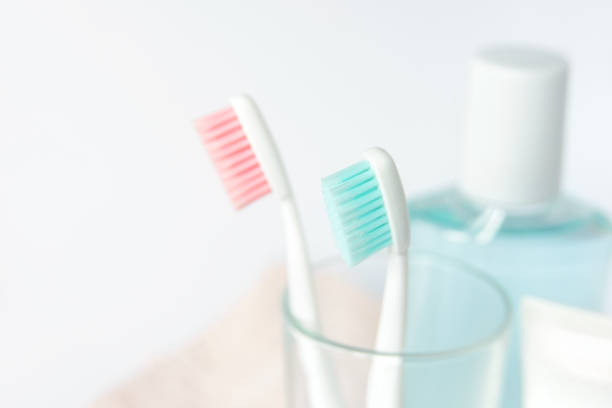 zahnbürsten, zahnpasta, spülen und handtuch auf weißem hintergrund. zahnmedizinische und medizinische konzept. kostenloses exemplar raum. - toothbrush pink turquoise blue stock-fotos und bilder