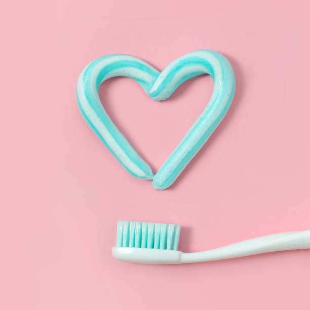 zahnbürsten und zahnpasta türkise farbe in form von herzen auf rosa hintergrund. zahnmedizinische und medizinische konzept. - toothbrush pink turquoise blue stock-fotos und bilder