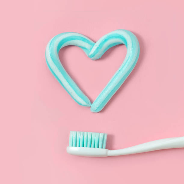 escovas de dentes e pasta dentífrica cor turquesa em forma de coração no fundo rosa. conceito de saúde e odontológico. - toothbrush pink turquoise blue - fotografias e filmes do acervo