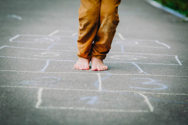kid playing hopscotch on playground, kids outdoor activities