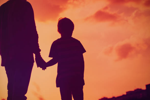 istock silhouette of father and son holding hands at sunset 956315978