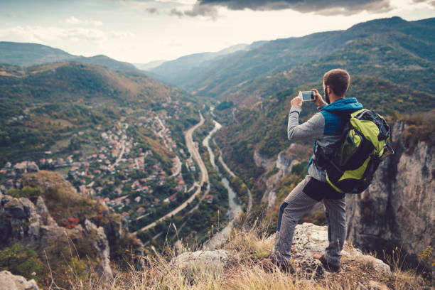istock Tourist man on the mountain top taking photos 956315992