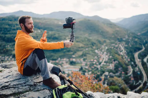 Tourist man sitting on the rocks and vlogging